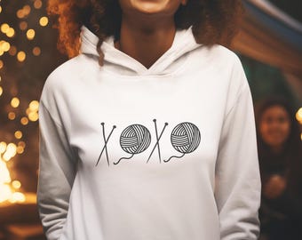 May include: White hoodie with a black graphic of yarn balls and knitting needles, with the text "XOXO" in the center.
