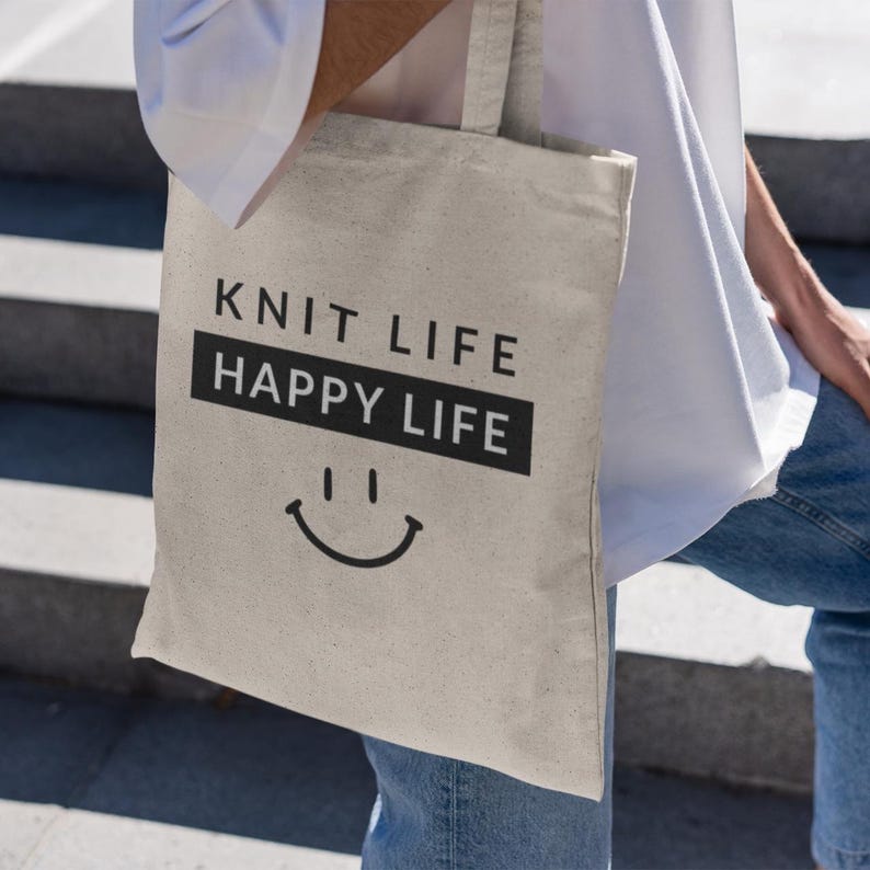 woman outside in jeans and white shirt holding canvas bag title "Knit Life Happy Life"