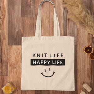 Tote bag on wood floor that says "Knit Life Happy Life"