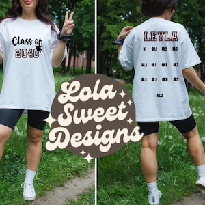 May include: White t-shirt with the text "Class of 2040" printed in maroon on the front. The back of the shirt has the name "LEYLA" printed in maroon with a list of grades and numbers underneath.