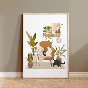 May include: A framed art print featuring an illustrated interior scene. A brown armchair holds two cats, one white and one black. Potted plants and a shelf with decor are also depicted. The artwork has a neutral color palette with a cozy, inviting feel.