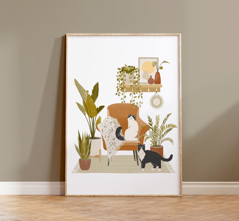 May include: A framed art print featuring an illustrated interior scene. A brown armchair holds two cats, one white and one black. Potted plants and a shelf with decor are also depicted. The artwork has a neutral color palette with a cozy, inviting feel.