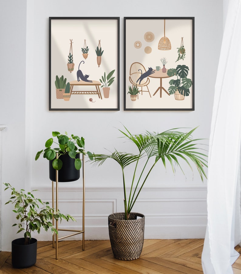 May include: Two framed art prints with black frames depict cats and plants in a minimalist style. The prints are displayed above a collection of potted plants, including a palm and a plant in a black pot on a gold stand. The room has a wooden floor.