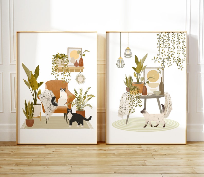May include: Two framed art prints featuring interior scenes with cats and plants. One print shows a cat on a chair, surrounded by potted plants. The other print depicts a cat near a table with plants and hanging lamps. Both prints have a gold frame.