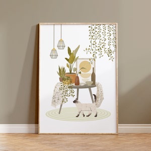 May include: A framed art print featuring a cozy interior scene. A round table displays potted plants, a vase, and a framed artwork. A Siamese cat walks on a rug in front of the table. The print has a neutral color palette with green and yellow accents.