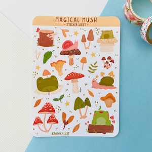 Peut inclure: Une planche d'autocollants intitulée "MAGICAL MUSH" avec des illustrations de champignons, d'escargots et d'une grenouille. Les autocollants sont de couleurs variées, notamment rouge, marron, vert et jaune. La feuille est rectangulaire avec des coins arrondis.