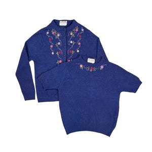 May include: Two-piece blue knit sweater set. The long-sleeve cardigan and short-sleeve top feature floral embroidery in pink, red, and green. The set is displayed on a white background.