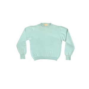 May include: A light blue crew neck sweater with long sleeves. The sweater has ribbed cuffs and a ribbed hem. The neckline has a small tag. The sweater is made of a soft, lightweight material.