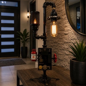 May include: A black metal pipe lamp featuring two light sources, one with a mesh cage and one with an exposed Edison bulb. The base includes a small red LP GAS canister, a red valve handle, and decorative gold-colored gears on a rectangular box.