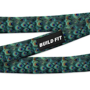 May include: A green and blue exercise resistance band with a peacock feather pattern. The band has the text "BUILD FIT" printed on it.