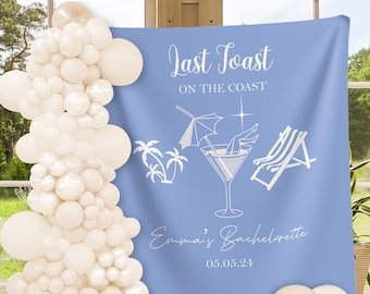 Pode incluir: Um fundo azul claro com texto e ilustrações brancas para uma despedida de solteira. O texto diz "Last Toast on the Coast" e "Emma's Bachelorette 05.05.24". Um arco de balões e balões espalhados estão na imagem.
