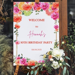 Könnte beinhalten: Ein weißes Schild auf einer Staffelei mit der Aufschrift "WELCOME TO Hannah's 50TH BIRTHDAY PARTY 06.06.2025". Verziert mit Aquarellblumen und Zitrusfrüchten. Eine Blumengesteck befindet sich unten.