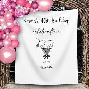 May include: White backdrop with black text that reads "Emma's 40th Birthday celebration" and "05.05.2024". A black and white illustration of a martini glass with a woman's legs sticking out of the glass and an umbrella on the rim.