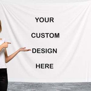 May include: A woman points to a white backdrop with the text "YOUR CUSTOM DESIGN HERE" printed on it.