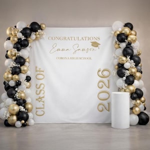 Könnte beinhalten: Ein weißer Abschluss-Hintergrund mit goldenem Text und Ballonbögen. Der Text lautet "GRATULATION Emma Samson" und "CORONA HIGH SCHOOL" mit "KLASSE VON" und "2026". Die Ballonbögen zeigen schwarze, goldene und weiße Ballons.