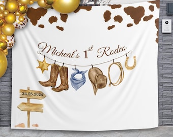 Może przedstawiać: Białe tło z brązową obwódką w wzór krowy. Tekst "Micheal's 1st Rodeo" jest napisany brązowym kursywą. Na sznurze do suszenia wiszą: kowbojski kapelusz, buty, bandana, lasso i podkowa.