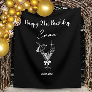 Könnte beinhalten: Schwarzer Hintergrund mit weißem Text, der "Happy 21st Birthday Emma 05.05.2024" lautet. Eine weiße Silhouette eines Martini-Glases mit Frauenbeinen im Glas und einem Regenschirm befindet sich in der Mitte des Hintergrunds.