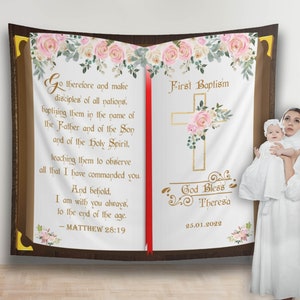 Puede incluir: Un fondo blanco con una gran imagen de un libro abierto. El libro tiene una cubierta marrón con detalles dorados y diseños florales rosas. La página izquierda tiene un versículo bíblico de Mateo 28:19. La página derecha tiene las palabras "Primer Bautismo" y "Dios bendiga a Teresa" con la fecha 25.01.2022. Una mujer con un vestido blanco sostiene a un bebé con un vestido blanco.