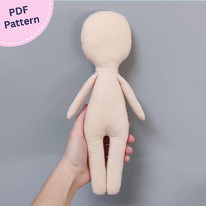 Op de afbeelding: Een lichtbeige stoffen pop met een rond hoofd, slanke armen en benen, met een eenvoudig, gelaatloos ontwerp. De pop wordt gepresenteerd als een PDF Pattern, zoals aangegeven door de tekst in de linkerbovenhoek van de afbeelding.
