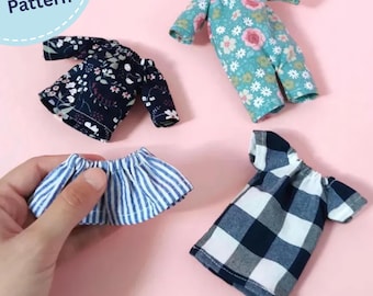 May include: Four miniature doll garments including a teal floral jumpsuit, a black floral top, a blue and white striped skirt, and a black and white buffalo plaid top. The image includes the text PDF Pattern in a light blue circular graphic.
