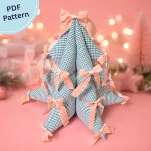 May include: A fabric Christmas tree decoration featuring a blue and white gingham pattern. The tree is adorned with multiple small, light peach-colored fabric bows attached to its points and sides. A PDF Pattern label is visible in the corner.