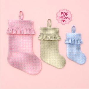 May include: Three fabric stockings in descending sizes, featuring a gingham check pattern in pink, olive green, and light blue. Each stocking has a ruffled cuff and a hanging loop at the top. A pink scalloped badge displays the text PDF pattern.