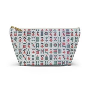 May include: White zippered makeup bag with a pattern of Chinese mahjong tiles in red, green, and black.