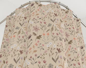 May include: A beige shower curtain with a floral pattern. The design features various flowers in shades of pink, purple, white, and orange, along with green leaves and stems. The curtain is hanging from a curved, silver-colored shower rod.