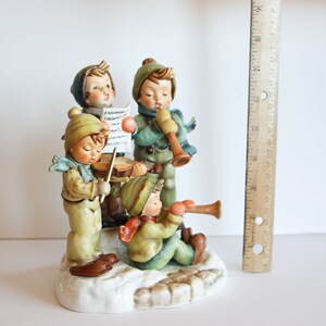 K&ouml;nnte beinhalten: Eine Figuren-Gruppe aus vier Kindern, die Musik machen. Die Kinder sind in Winterkleidung gekleidet und halten Musikinstrumente in der Hand. Die Figur ist aus Porzellan und in leuchtenden Farben bemalt.