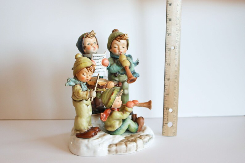 K&ouml;nnte beinhalten: Eine Figuren-Gruppe aus vier Kindern, die Musik machen. Die Kinder sind in Winterkleidung gekleidet und halten Musikinstrumente in der Hand. Die Figur ist aus Porzellan und in leuchtenden Farben bemalt.
