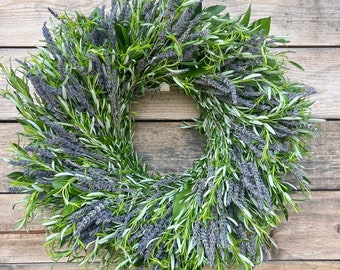 Puede incluir: Una corona hecha de lavanda y romero, colgada en una pared de madera.