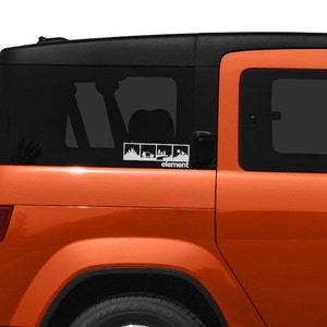 May include: An orange car with a white decal on the back window. The decal features three images of a car driving through a forest, a car driving through a desert, and a car driving up a mountain. The text "element" is below the images.