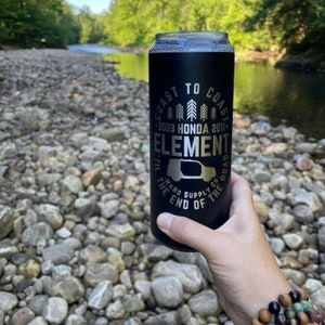 May include: Black insulated can cooler with a silver design featuring the text "Coast to Coast 2003 Honda 2011 Element 'Til the End of the Road and Supply Co."