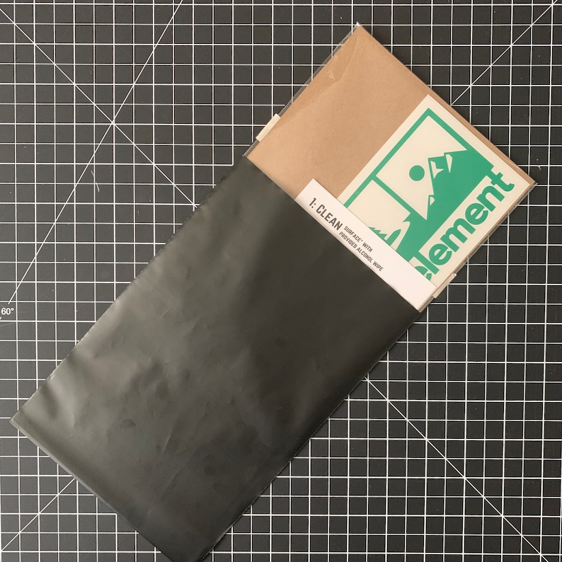 May include: A black envelope with a brown envelope inside. The brown envelope has a white sticker with the text "1: CLEAN SURFACE WITH PROVIDED ALCOHOL WIPE" and a green and white logo with the text "element".