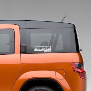 May include: An orange Honda Element with a white decal on the back window. The decal features a series of four images depicting a car driving through different landscapes, with the word "element" below the images.