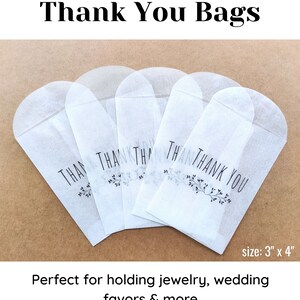 May include: Five white thank you bags with black text and a small floral design. The bags are 3 inches by 4 inches.