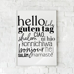 May include: A white framed print with black text that says "hello hola guten tag ciao shalom ni hao konnichiwa bonjour hej salam namaste".