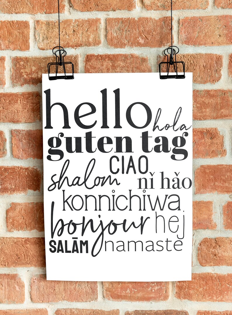 May include: A white poster with black text that says "hello hola guten tag shalom CIAO ni hao konnichiwa bonjour hej SALAM namaste" hanging on a brick wall.