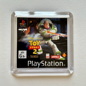 May include: A clear plastic case containing a PlayStation game cartridge for Toy Story 2. The game cover features Buzz Lightyear in a space suit, with the game title and PlayStation logo. The game is rated G8+.