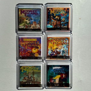 Puede incluir: Seis portadas de cajas de juegos diferentes para la serie de videojuegos Monkey Island. Las portadas presentan diferentes personajes y escenas de los juegos. Los juegos se titulan "The Secret of Monkey Island", "EChuck's Revenge", "The Curse of Monkey Island", "Escape from Monkey Island", "Tales of Monkey Island", y "Return to Monkey Island".