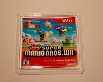 Może przedstawiać: Przezroczysta plastikowa obudowa z czerwoną, białą i zieloną kasetą do gier wideo w środku. Kaseta jest do gry "New Super Mario Bros. Wii" na konsolę Wii. Obudowa ma na przodzie zdjęcie Mario, Luigiego, Peach, Toad i Yosh.