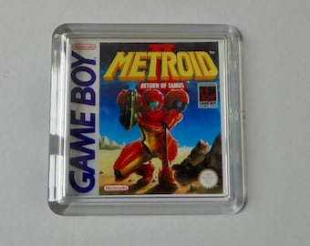 Könnte beinhalten: Ein transparentes Plastikgehäuse mit einer Game Boy-Cartridge. Die Cartridge ist für das Spiel Metroid II: Return of Samus. Das Spiel ist ein klassischer Nintendo-Titel.