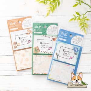 Puede incluir: Tres paquetes de notas adhesivas de doble cara con diseños coloridos. Cada paquete tiene dos hojas de notas con un diseño diferente. Los diseños incluyen café, pasteles y una computadora portátil. El texto en las notas dice "裏もかわいい フルカラー デザイン!" que se traduce como "¡La parte de atrás también es linda! ¡Diseño a todo color!"