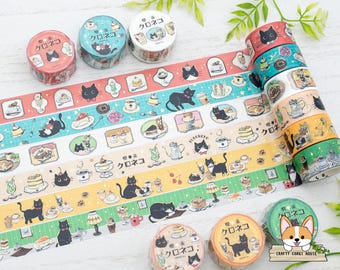 May include: Decorative washi tape rolls featuring black cats, desserts, and Japanese text. The tape designs include various colors and patterns with illustrations of cats, cakes, and drinks. The rolls are perfect for scrapbooking and crafting.