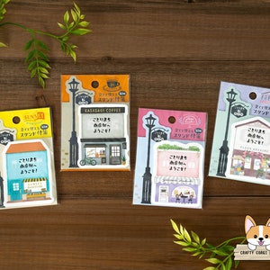 May include: Four colorful shop-themed sticky notes with a street lamp design. Each note features a different shop name and a welcome message in Japanese. The notes are packaged in clear plastic bags.