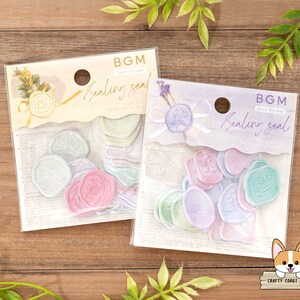 May include: Two packages of pastel colored wax sealing stickers. The stickers are in the shape of a circle and have different designs. The packages are labeled "BGM Deco Sticker Sealing Seal".