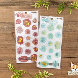 May include: Two sheets of sticker paper featuring Moomin characters. The stickers are on a white background with a light blue and pink color scheme. The stickers are in the shape of circles and ovals. The stickers feature Moomin characters, including Moomin, Sniff, and Little My.