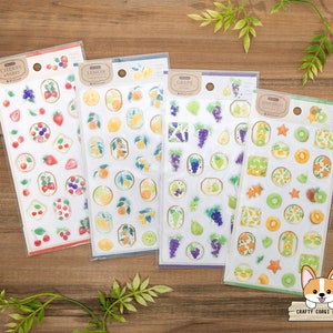 May include: Four sheets of colorful fruit-themed stickers. Each sheet features a different fruit: cherries, lemons, grapes, and kiwi. The stickers are printed on clear plastic and have a glossy finish.