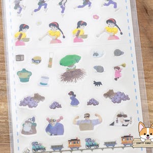 May include: A sheet of colorful stickers featuring various illustrations. The stickers include images of a girl in a yellow dress, a green tree, a black cat, and a train. The stickers are in a clear plastic sheet.