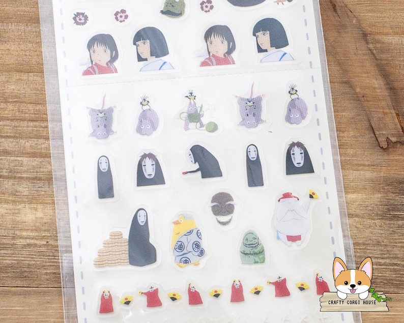 May include: A sheet of clear stickers featuring various characters from the animated film, Spirited Away. The stickers include images of Chihiro, No-Face, and other iconic characters in vibrant colors. The stickers are arranged on a white backing.